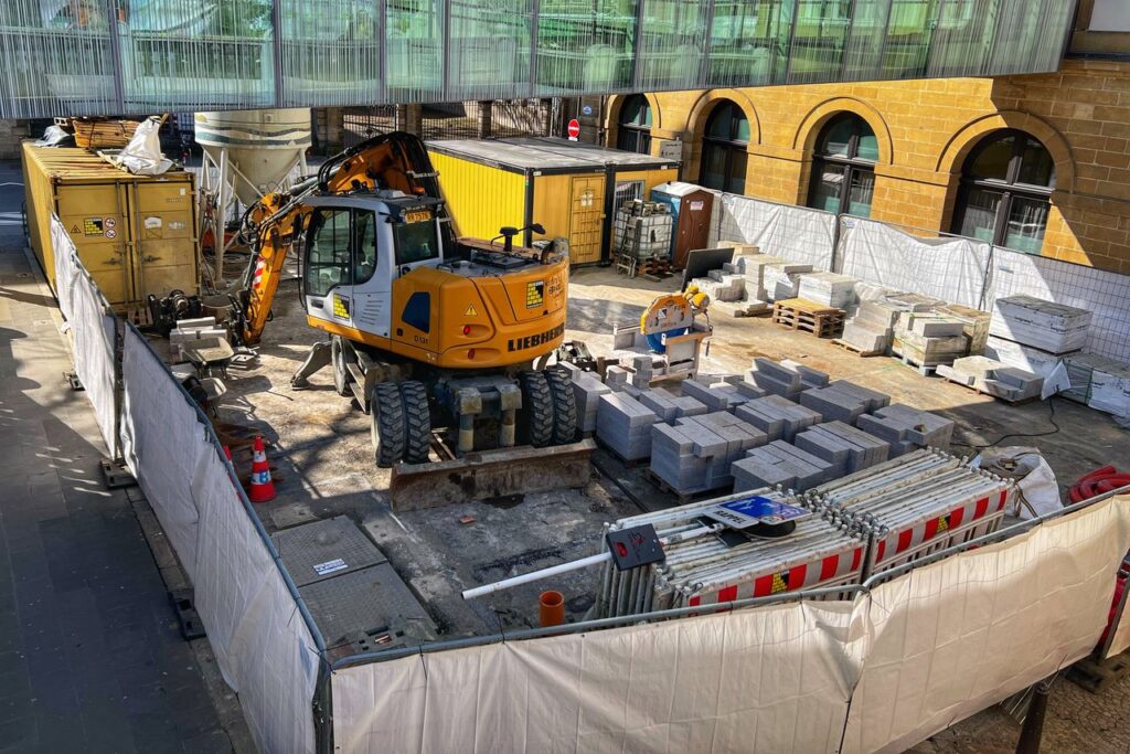 A construction site with machinery and materials in an urban setting during daytime.